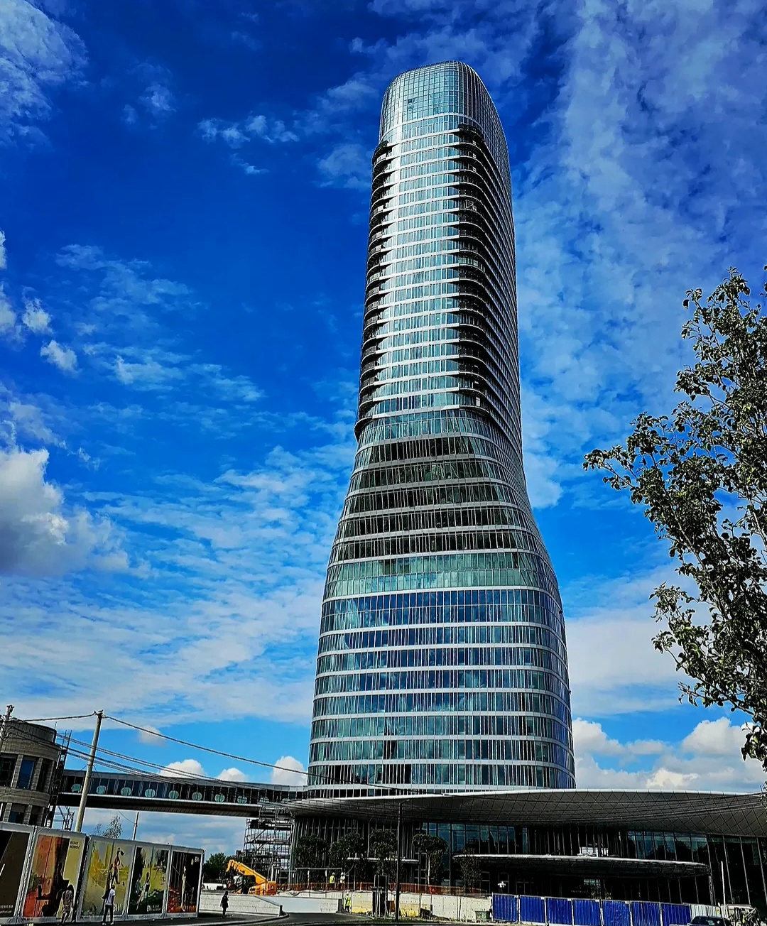Curved glass skyscraper rising into a blue sky