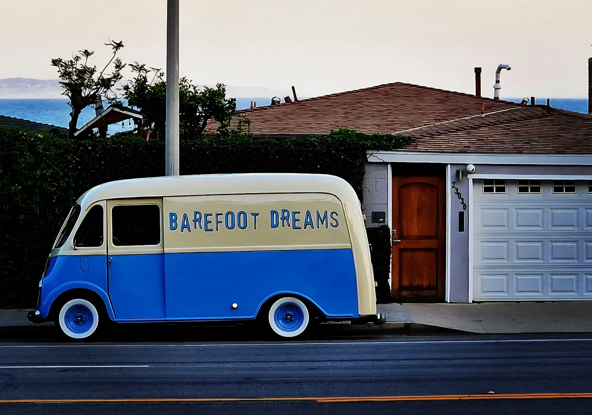 Blue and cream Barefoot Dreams vintage van parked beside a coastal home