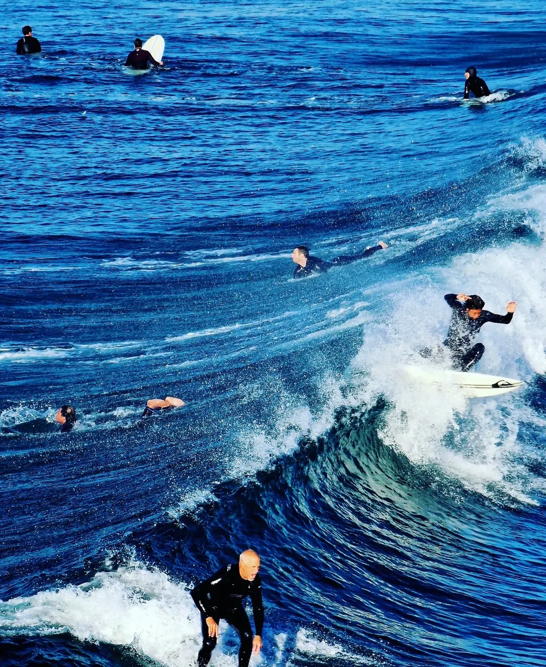 Surfers riding and waiting for waves in blue ocean water