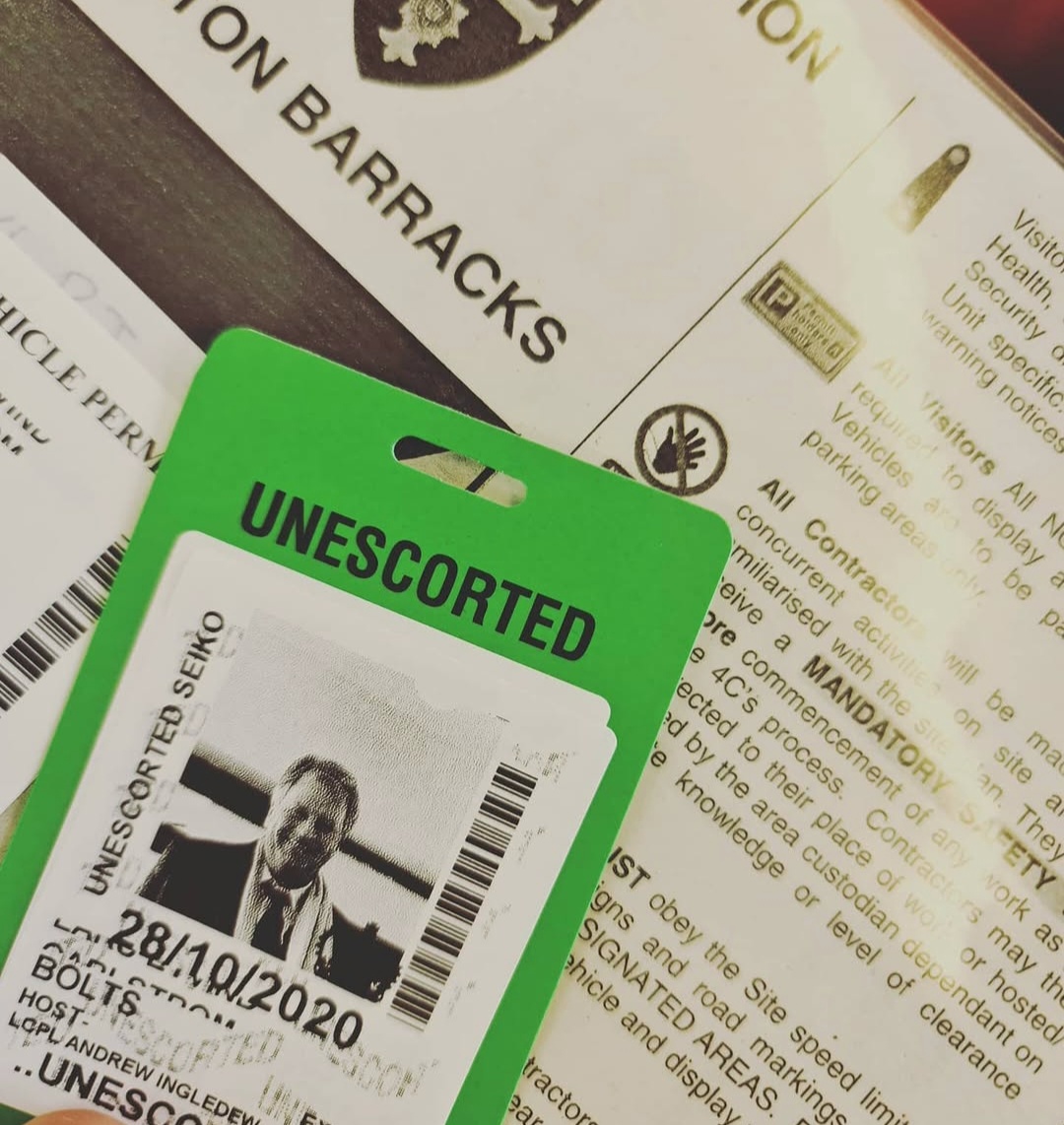 Green visitor pass resting on printed visitor information