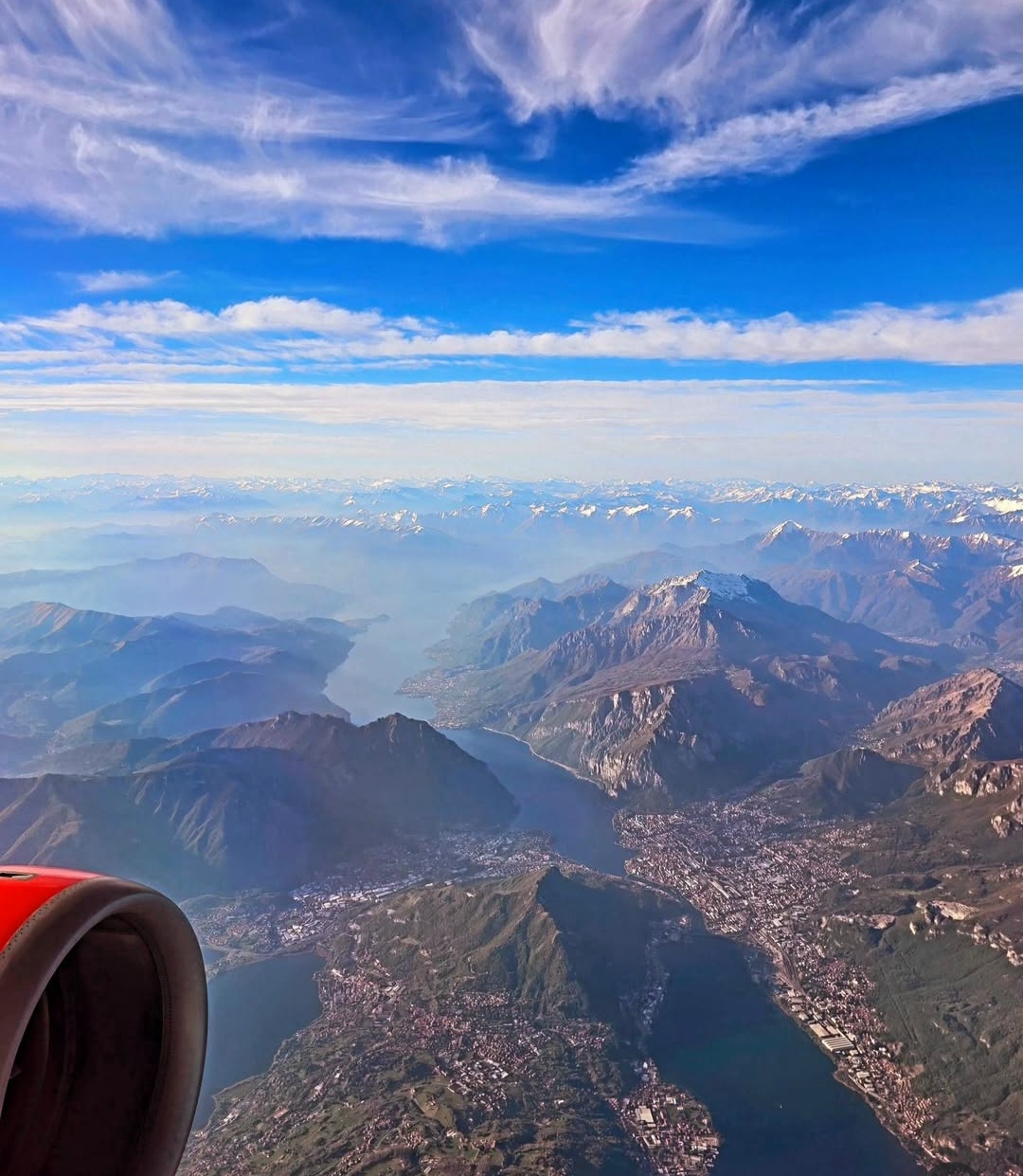 Mountain lakes seen from an aircraft beside a red engine