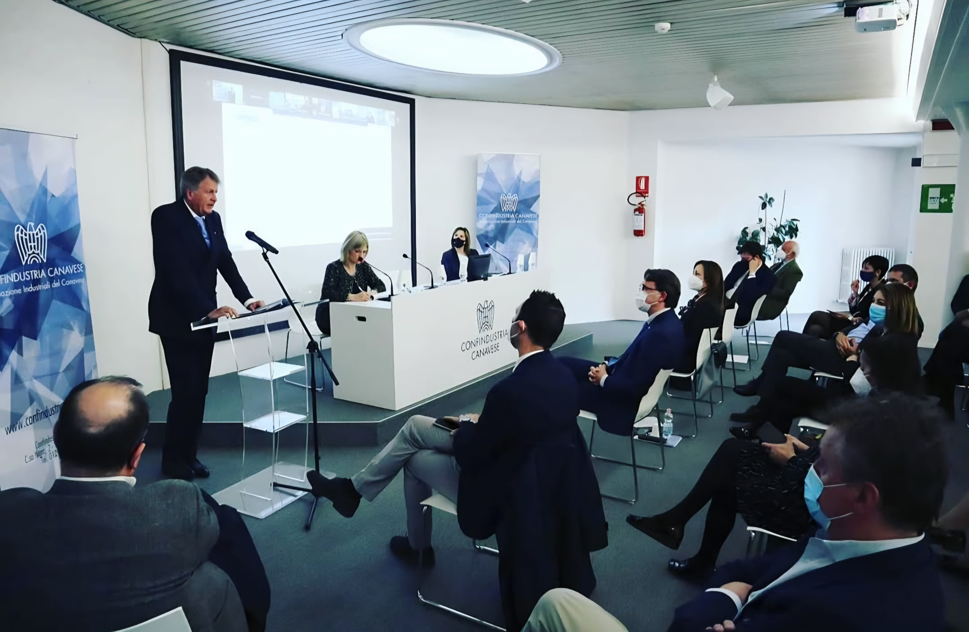 Speaker addressing an audience at a Confindustria Canavese event