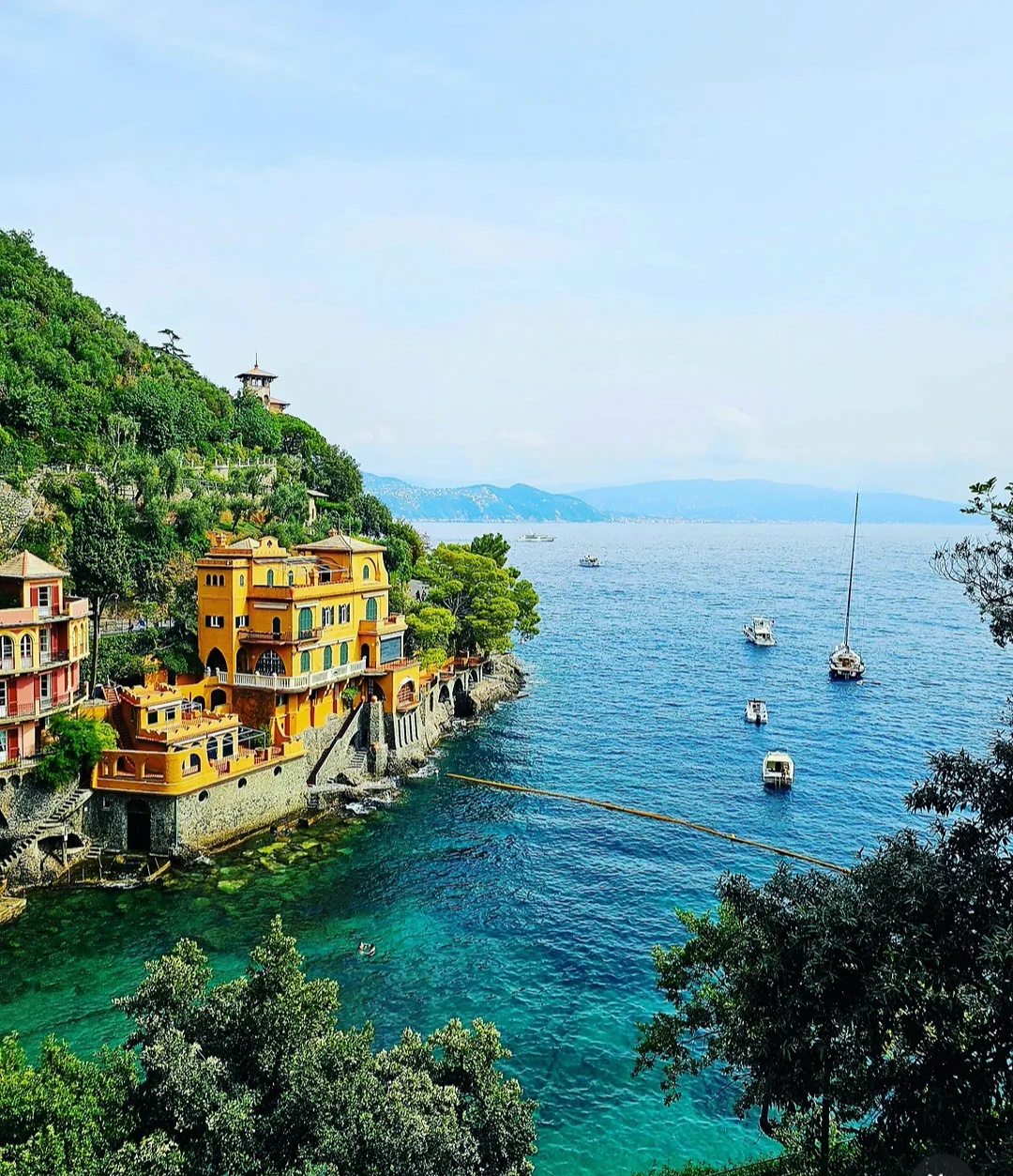 Colourful coastal villas above turquoise water and anchored boats