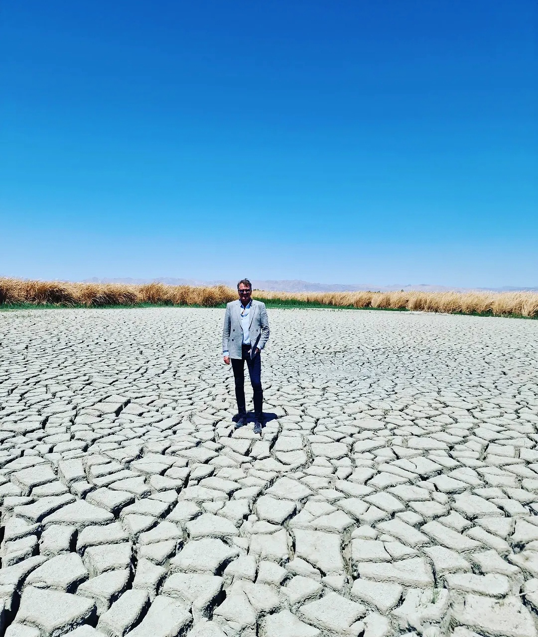 Lars Carlstrom standing on cracked dry ground beneath a blue sky