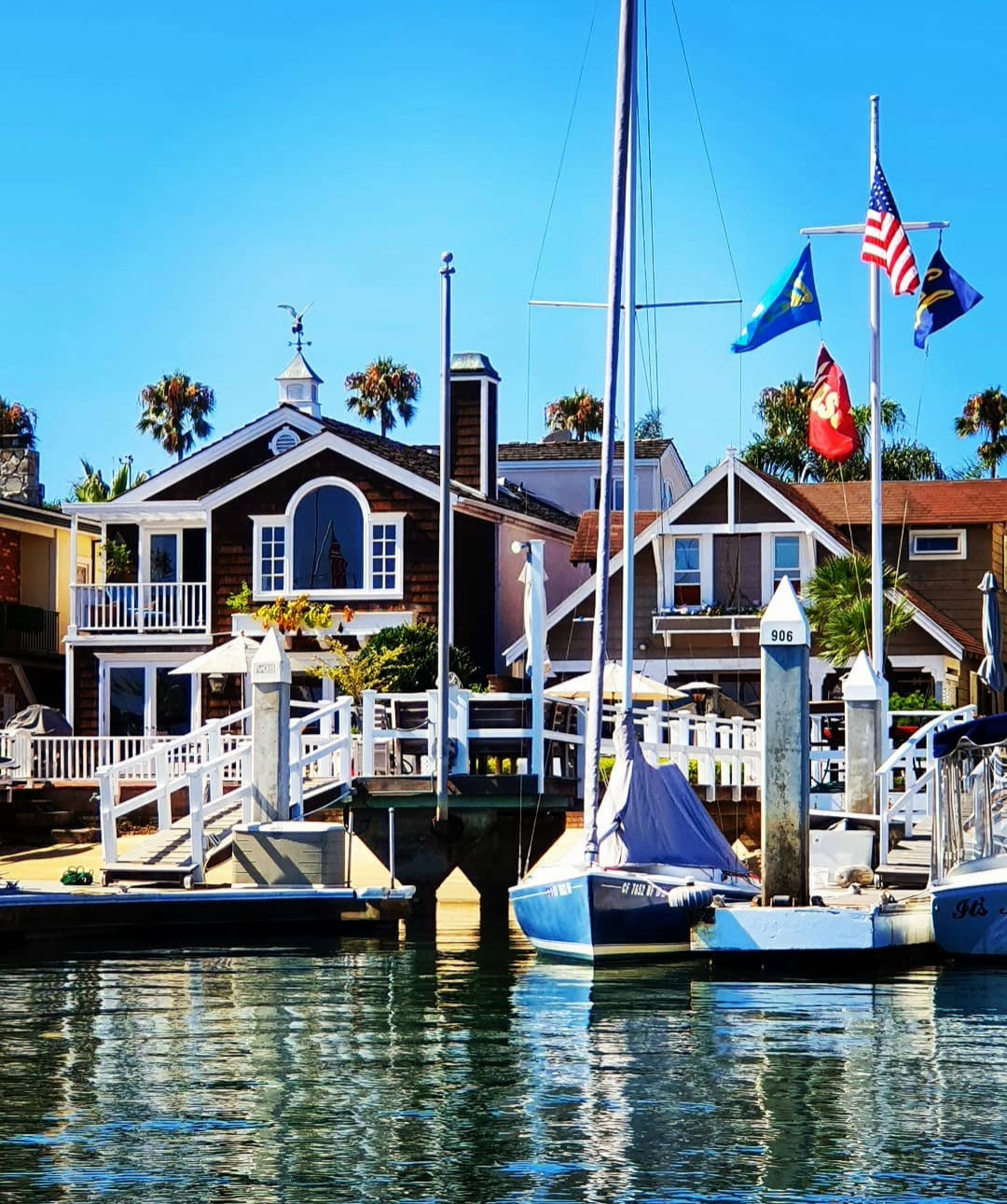 Sailboats and waterfront houses beneath palm trees and flags