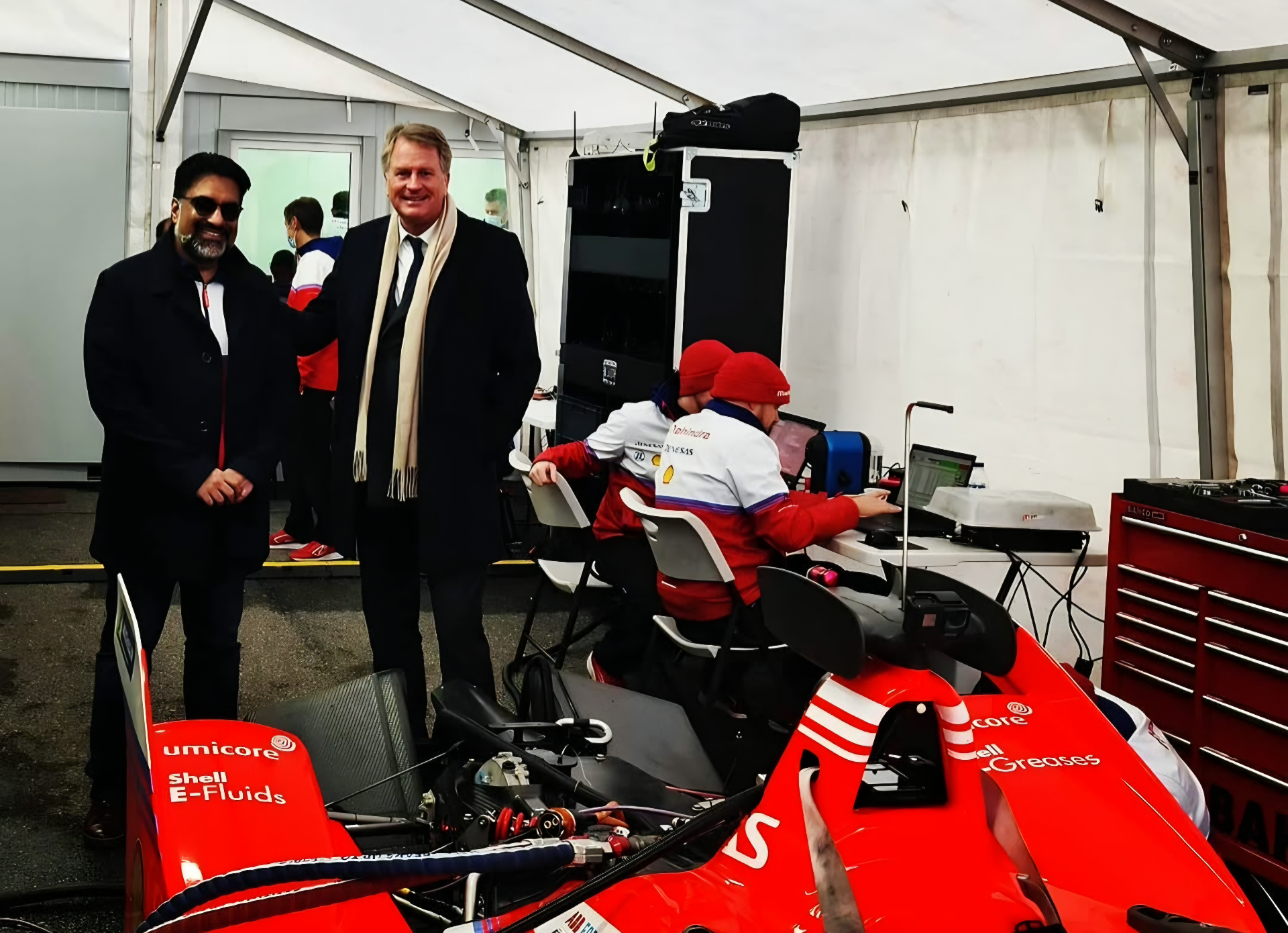 Lars Carlstrom and a companion beside a red racing car in a paddock tent