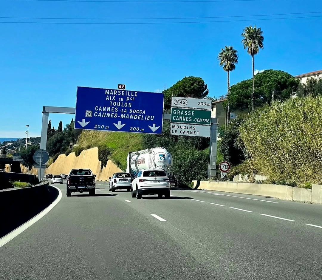 Palm-lined motorway with signs towards Cannes, Grasse and Marseille