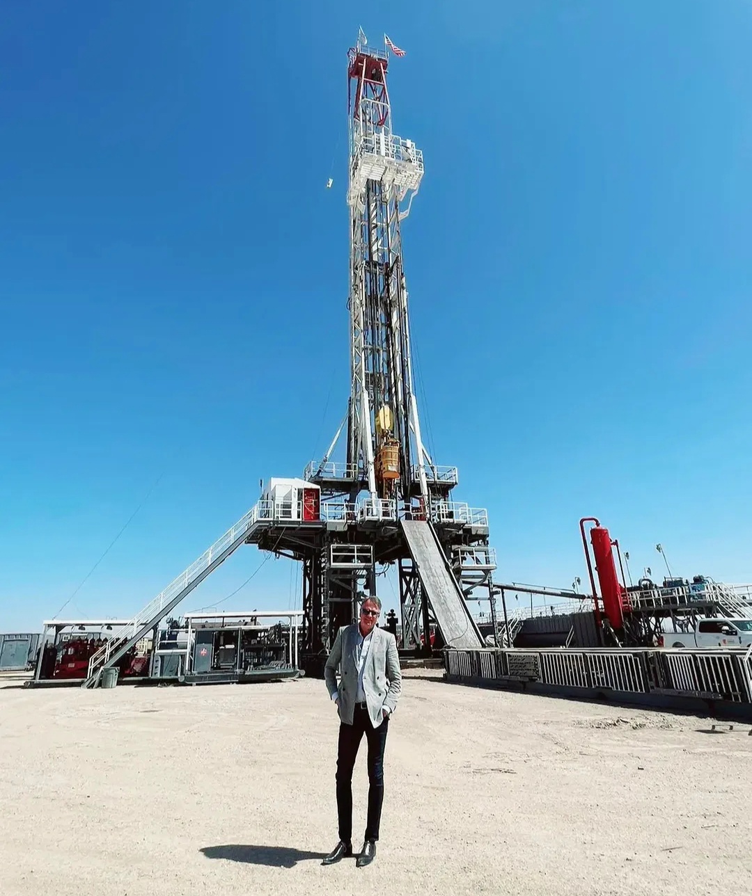 Lars Carlstrom standing in front of a drilling rig beneath a clear blue sky